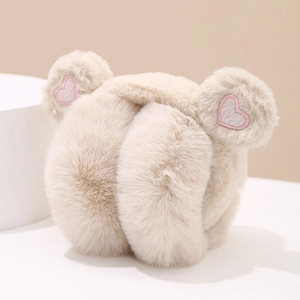 Close-up of soft beige plush earmuffs featuring pink sequin heart embroidery on bear ears