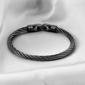 Detailed close-up of dark grey cable wire woven bracelet with a steel clasp on silk