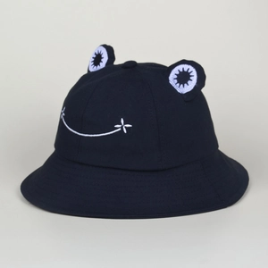Close-up of the black cotton bucket hat featuring 3D frog eyes and a white smile embroidery
