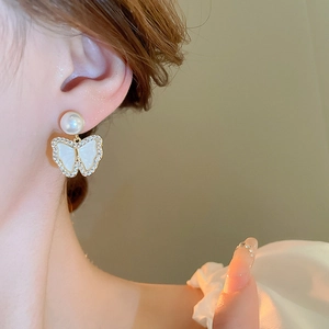 Detail of elegant butterfly pearl earring with sparkling zircons on model side profile