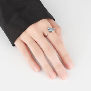 Adjustable silver butterfly spinner ring with blue crystals on woman's finger