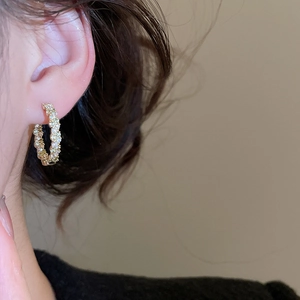 Vue détaillée des boucles d'oreilles dorées avec perles blanches et zircons sur l'oreille