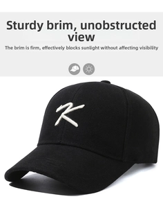 Detail of white embroidered K letter on black cotton baseball cap with stiff brim