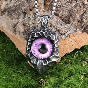Macro shot of stainless steel evil eye pendant with purple iris on mossy bark base