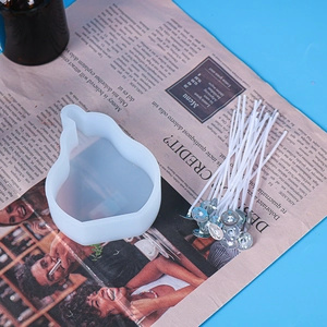 Makro-Detail von birnenförmiger Silikonform und Kerzendochten auf einem Zeitschriftenhintergrund