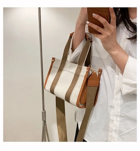 Detail showing white canvas and brown leather contrast stitching on crossbody bag