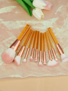 Detail showing 9 cosmetic brushes with amber transparent handles on champagne silk fabric