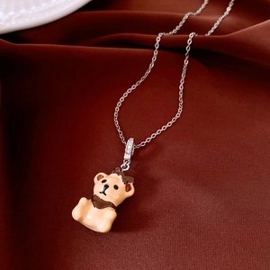 Detail of yellow enamel bear pendant with scarf and crystals on satin background