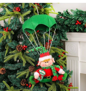 Detail view of a handmade Christmas elf ornament with green parachute hanging on a tree