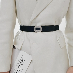 Detail of black elastic waist belt with silver rhinestone buckle on white blazer