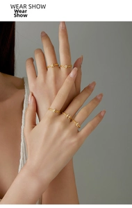 Detail of elegant gold chain rings with sparkling zircon pavé initial charms on hands