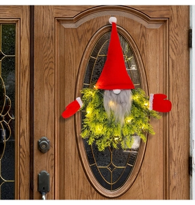 Close-up of lighted Christmas gnome wreath with red hat and grey beard on front door