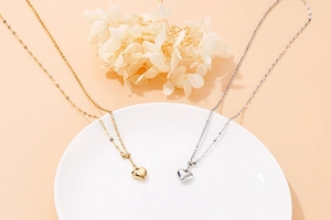 Detailed top view of gold and silver heart necklaces on a tray with dried flowers