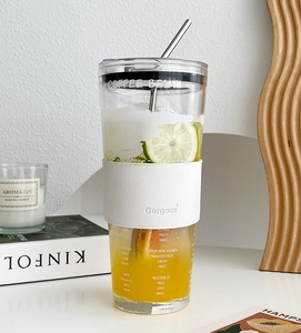 Detail of high-capacity glass tumbler with straw, leather sleeve, and coffee origin print