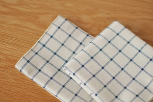 Detail of blue and white checkered linen napkin with textured stitching on wood background