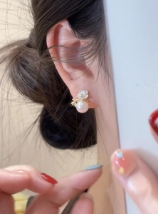 Detailed view of an elegant 18k gold plated flower pearl stud earring on model ear