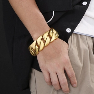 Detailed view of heavy cuban link chain bracelet in polished gold on male wrist