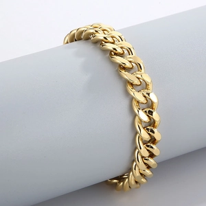 Gros plan d'un bracelet gourmette en or poli sur un piédestal gris minimaliste