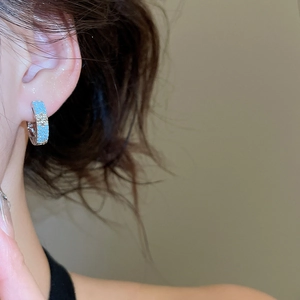 Close-up of silver hoop earring with light blue pave stones on model's ear