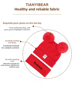 Detail view of red knitted baby hat with dual pom-poms and matching neck warmer scarf