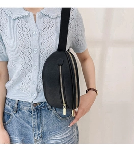 Detail of black litchi leather waist bag with golden zipper and adjustable wide strap