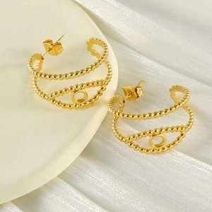 Golden geometric hollow stainless steel earrings displayed on elegant white silk fabric