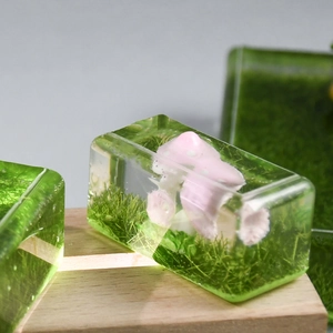Macro detail of artisan resin keycap featuring miniature moss and pink mushrooms