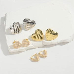 Textured gold and silver heart earrings with pearl inlay on minimalist white stone