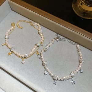 Detailed macro view of double-layer pearl bracelets with star charms and zircon beads