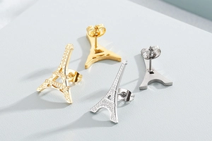 Détails de boucles d'oreilles Tour Eiffel en finitions or et argent sur fond bleu