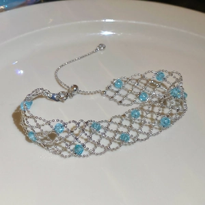 Detail of silver mesh bracelet with blue beads and adjustable drawstring clasp in a tray