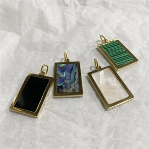 Detalle de cuatro colgantes rectangulares en acero dorado con nácar y piedras variadas
