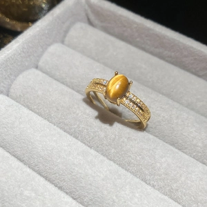 Close-up of gold-plated tiger eye ring with cat-eye effect and side-set pavé crystals