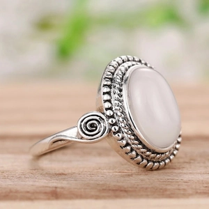 Detailaufnahme eines Retro-Silberrings mit großem ovalem weißem Opal und Gravuren