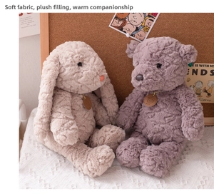 Detail of curly plush bear and rabbit dolls sitting on lace fabric with warm lighting