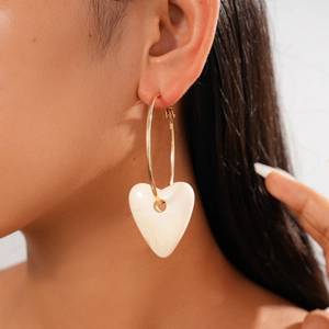 Fashionable golden hoop earring with cream marble heart pendant shown on model