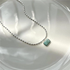 Macro shot of 925 sterling silver olive bead chain with rectangular green gemstone pendant