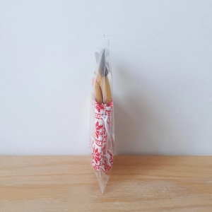 Close-up of a festive knitted Christmas gift bag with a plush reindeer in clear packaging