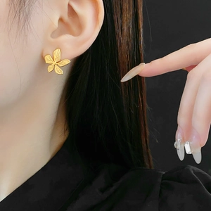 Detail of matte gold flower earring on model with five-petal metallic petal texture