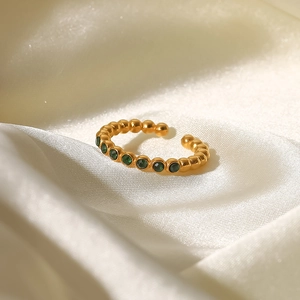 Macro detail of 18K gold beaded ring featuring green zircon stones on silk background