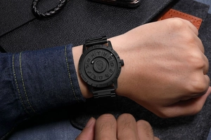 Detail of black magnetic ball watch featuring skull dial and zodiac engravings on wrist