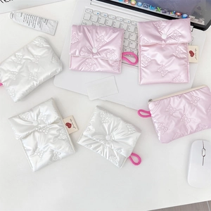 Quilted bow texture pouches in white and pink displayed on a desk with laptop