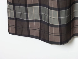 Detail of classic plaid coat hem featuring dark grey, olive green, and brown weave