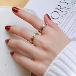 Close-up of golden ancient Chinese coin motif rings on a hand with red manicure.