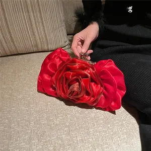 Detail of red silk rose evening bag with layered fabric petals and silver metal clasp