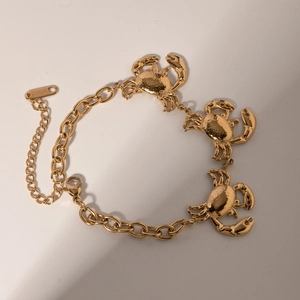 Detail of golden stainless steel chain bracelet with three intricate crab pendants