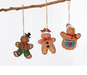 Three gingerbread man resin ornaments hanging on a wooden branch for Christmas decor