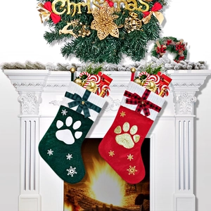 Detail view of red and green Christmas pet stockings with sequin paw prints on fireplace