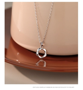 Macro shot of polished silver Mobius pendant on a brown dish with mirror reflection