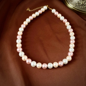 Détail d'un collier de perles vintage avec perles blanches roses pêches sur soie